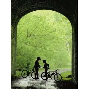  Two Silhouetted Cyclists Stop in a Tunnel on a Bike Trail 